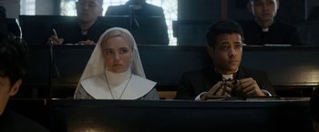 Movie still from “Prey for the Devil” (2022), directed by Daniel Stamm – A nun sitting next to a man in a church; Medium shot, High angle