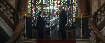 Movie still from “Prey for the Devil” (2022), directed by Daniel Stamm – A couple of people standing next to each other in front of a stained glass window; Wide shot, Low angle