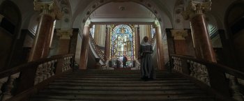 Movie still from “Prey for the Devil” (2022), directed by Daniel Stamm – A woman standing on the stairs in front of a stained glass window; Extreme Wide shot, Low angle
