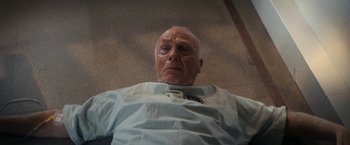 Movie still from “Prey for the Devil” (2022), directed by Daniel Stamm – An older man is laying on the ground; Close Up shot, Overhead angle