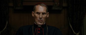 Movie still from “Prey for the Devil” (2022), directed by Daniel Stamm – A person wearing a priest's outfit; Close Up shot, Low angle