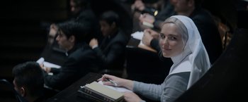 Movie still from “Prey for the Devil” (2022), directed by Daniel Stamm – A woman sitting in front of a group of people at a table; Close Up shot, Over the shoulder angle