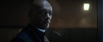 Movie still from “Prey for the Devil” (2022), directed by Daniel Stamm – An older man with a beard wearing a necklace; Close Up shot, Low angle