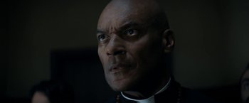 Movie still from “Prey for the Devil” (2022), directed by Daniel Stamm – A person wearing a priest's outfit; Close Up shot, Low angle