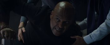 Movie still from “Prey for the Devil” (2022), directed by Daniel Stamm – A man with a bald head is looking at the camera; Close Up shot, Overhead angle