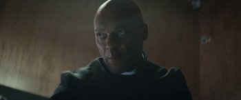 Movie still from “Prey for the Devil” (2022), directed by Daniel Stamm – A bald man is looking into the camera; Close Up shot, Low angle