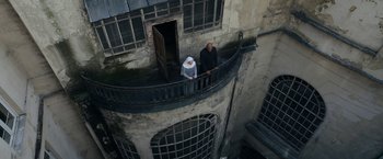 Movie still from “Prey for the Devil” (2022), directed by Daniel Stamm – A man and a woman standing on the balcony of an old building; Extreme Wide shot, Overhead angle