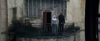 Movie still from “Prey for the Devil” (2022), directed by Daniel Stamm – A man and a woman standing on a balcony; Wide shot, Low angle