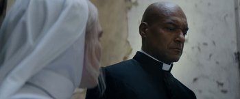 Movie still from “Prey for the Devil” (2022), directed by Daniel Stamm – A man and a woman dressed up in a priest's outfit; Close Up shot, Over the shoulder angle
