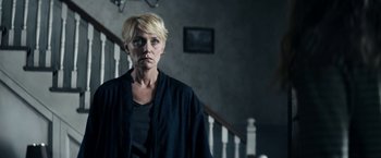 Movie still from “Prey for the Devil” (2022), directed by Daniel Stamm – A woman standing in a dark room next to a staircase; Medium shot, Low angle