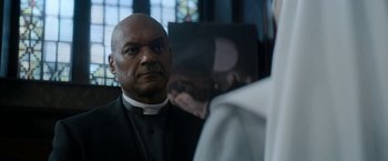 Movie still from “Prey for the Devil” (2022), directed by Daniel Stamm – A man wearing a priest's outfit looking at a woman; Close Up shot, Over the shoulder angle