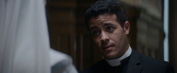 Movie still from “Prey for the Devil” (2022), directed by Daniel Stamm – A man wearing a priest's outfit looking at the camera; Close Up shot, Over the shoulder angle