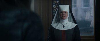 Movie still from “Prey for the Devil” (2022), directed by Daniel Stamm – A woman dressed as a nun in front of a stained glass window; Medium shot, Low angle