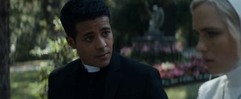 Movie still from “Prey for the Devil” (2022), directed by Daniel Stamm – A man in a black suit and white shirt; Close Up shot, Over the shoulder angle