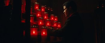 Movie still from “Prey for the Devil” (2022), directed by Daniel Stamm – A man standing in front of many lit candles; Medium shot, Low angle
