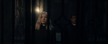 Movie still from “Prey for the Devil” (2022), directed by Daniel Stamm – A woman wearing a priest's outfit standing in front of a cross; Medium shot, Low angle