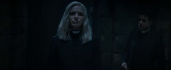 Movie still from “Prey for the Devil” (2022), directed by Daniel Stamm – A woman wearing a priest's outfit standing in a dark room; Close Up shot, Low angle