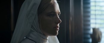 Movie still from “Prey for the Devil” (2022), directed by Daniel Stamm – A woman wearing a veil looking out of a window; Close Up shot, Low angle