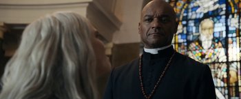 Movie still from “Prey for the Devil” (2022), directed by Daniel Stamm – A man in a priest's outfit and a woman in a black dress; Close Up shot, Low angle