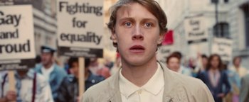 Movie still from “Pride” (2014), directed by Matthew Warchus – A young man is standing in front of a group of people; Close Up shot, Low angle