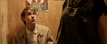 Movie still from “Pride” (2014), directed by Matthew Warchus – A man standing in front of a wall looking up at a poster; Medium shot, Over the shoulder angle