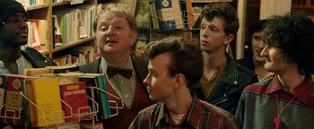 Movie still from “Pride” (2014), directed by Matthew Warchus – A group of men standing next to each other; Medium shot, Over the shoulder angle