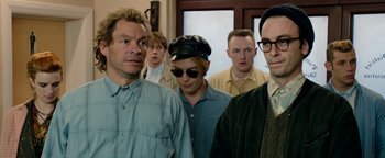 Movie still from “Pride” (2014), directed by Matthew Warchus – A group of people standing in front of a door; Medium shot, Over the shoulder angle