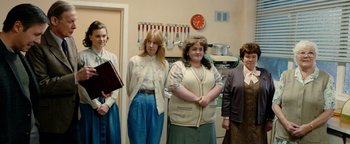 Movie still from “Pride” (2014), directed by Matthew Warchus – A group of people standing in a kitchen; Medium shot, Over the shoulder angle