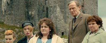 Movie still from “Pride” (2014), directed by Matthew Warchus – A group of people standing next to each other near a stone wall; Medium shot, Over the shoulder angle