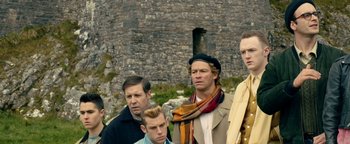 Movie still from “Pride” (2014), directed by Matthew Warchus – A group of men standing next to each other in front of a stone wall; Medium shot, Low angle