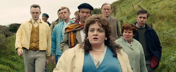 Movie still from “Pride” (2014), directed by Matthew Warchus – A group of people standing in a line with a woman; Medium shot, Over the shoulder angle