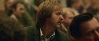 Movie still from “Pride” (2014), directed by Matthew Warchus – A person wearing a suit and tie; Close Up shot, Over the shoulder angle