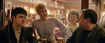 Movie still from “Pride” (2014), directed by Matthew Warchus – A woman sitting at a table with two glasses of beer in front of her; Medium shot, Over the shoulder angle