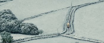 Movie still from “Pride” (2014), directed by Matthew Warchus – A car driving down a road in the middle of a snow covered field; Extreme Wide shot, Overhead angle