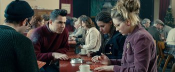 Movie still from “Pride” (2014), directed by Matthew Warchus – A group of people sitting at a table with cups; Medium shot, Over the shoulder angle