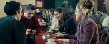 Movie still from “Pride” (2014), directed by Matthew Warchus – A group of people sitting at a table with plates of food; Medium shot, Over the shoulder angle