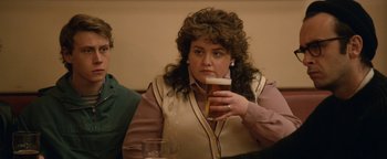 Movie still from “Pride” (2014), directed by Matthew Warchus – A woman sitting at a table holding a glass of beer; Close Up shot, Over the shoulder angle