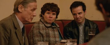Movie still from “Pride” (2014), directed by Matthew Warchus – A woman sitting next to two men in a restaurant; Close Up shot, Over the shoulder angle