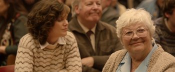 Movie still from “Pride” (2014), directed by Matthew Warchus – Two women and an old man are sitting in a crowd; Close Up shot, Over the shoulder angle