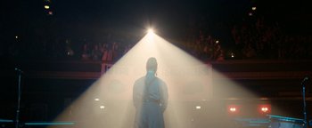 Movie still from “Pride” (2014), directed by Matthew Warchus – A man standing in front of an audience with a light shining on him; Extreme Wide shot, Low angle