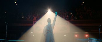 Movie still from “Pride” (2014), directed by Matthew Warchus – A man in a white suit holding up his arm in the air; Wide shot, Low angle