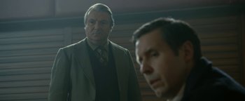 Movie still from “Pride” (2014), directed by Matthew Warchus – A man in a suit standing next to another man in a suit; Medium shot, Over the shoulder angle