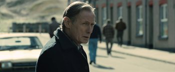 Movie still from “Pride” (2014), directed by Matthew Warchus – A person wearing a coat on the street; Close Up shot, Over the shoulder angle
