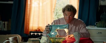 Movie still from “Pride” (2014), directed by Matthew Warchus – A man sitting at a table with a sewing machine; Medium shot, Low angle