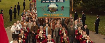 Movie still from “Pride” (2014), directed by Matthew Warchus – A large group of people are marching down the street; Wide shot, High angle