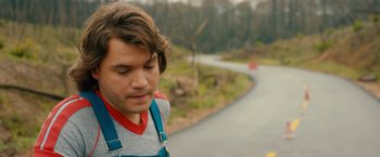Movie still from “Prince Avalanche” (2013), directed by David Gordon Green – A young man standing next to a winding road; Close Up shot, Over the shoulder angle