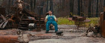 Movie still from “Prince Avalanche” (2013), directed by David Gordon Green – A man sitting on a chair in the middle of a field; Wide shot, High angle
