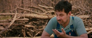 Movie still from “Prince Avalanche” (2013), directed by David Gordon Green – A man in a blue shirt is sitting in front of a tree; Close Up shot, Over the shoulder angle