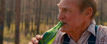 Movie still from “Prince Avalanche” (2013), directed by David Gordon Green – An older man drinking a bottle of beer; Close Up shot, High angle