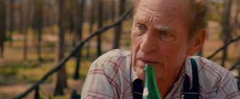 Movie still from “Prince Avalanche” (2013), directed by David Gordon Green – An older man with a beer in his mouth; Close Up shot, Over the shoulder angle